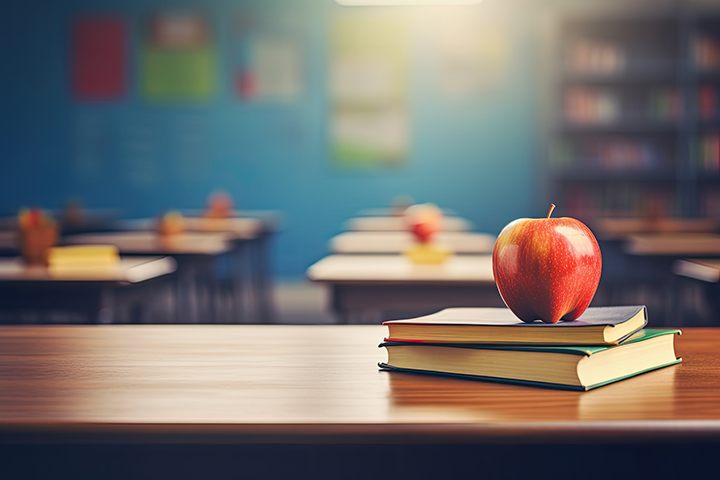 School teacher's desk with stack of books and apple. Education.