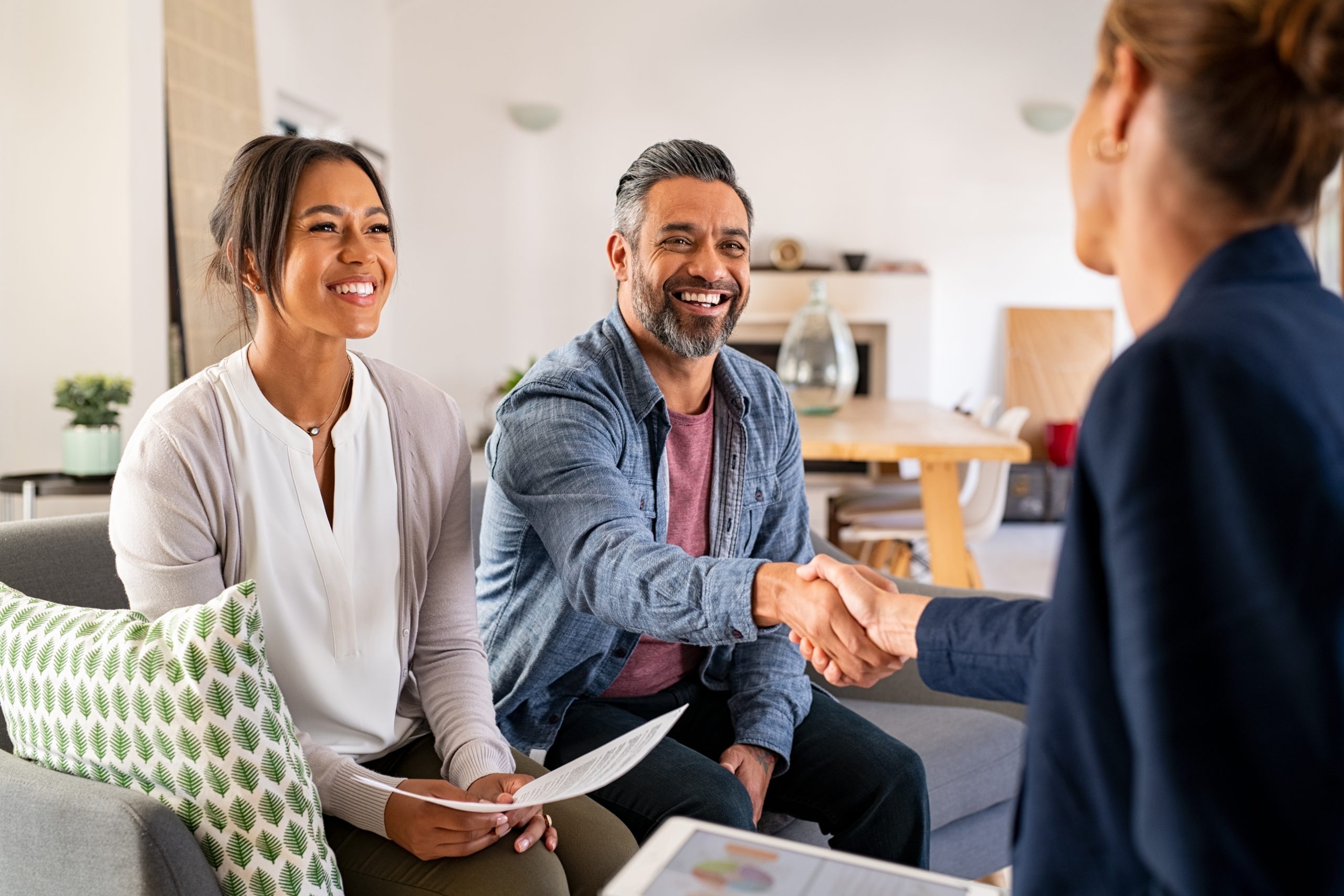 Multiethnic couple handshake with consultant at home