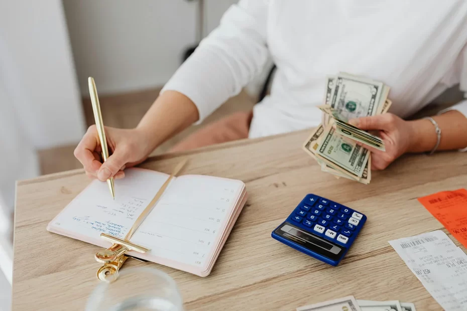 Woman writing in planner and holding cash