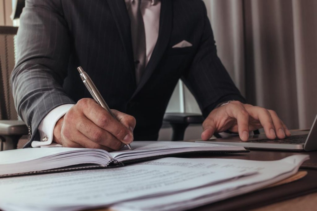 Hombre con traje escribiendo en un cuaderno