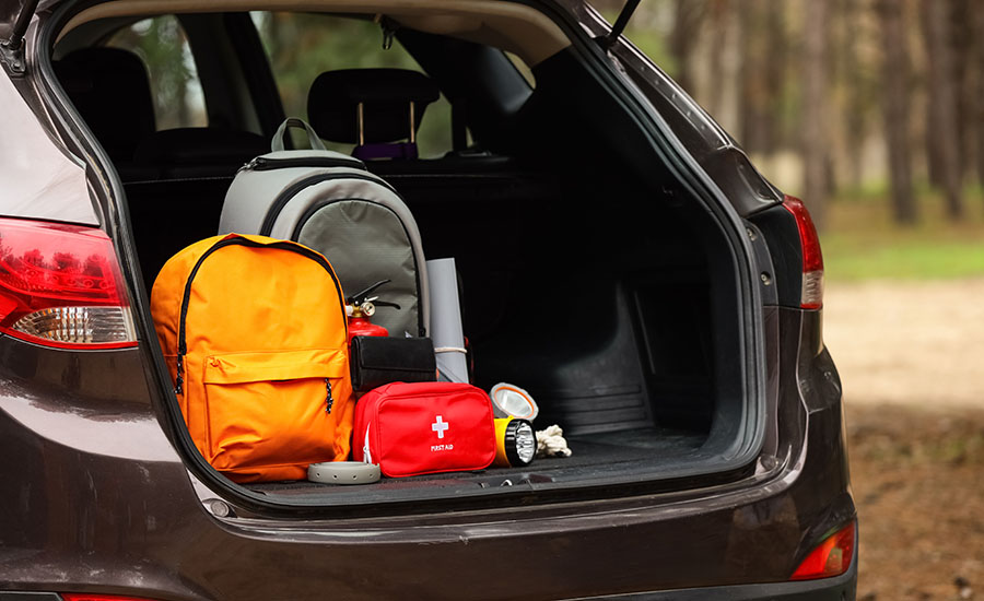 Emergency backpacks with necessities in open car trunk outdoors